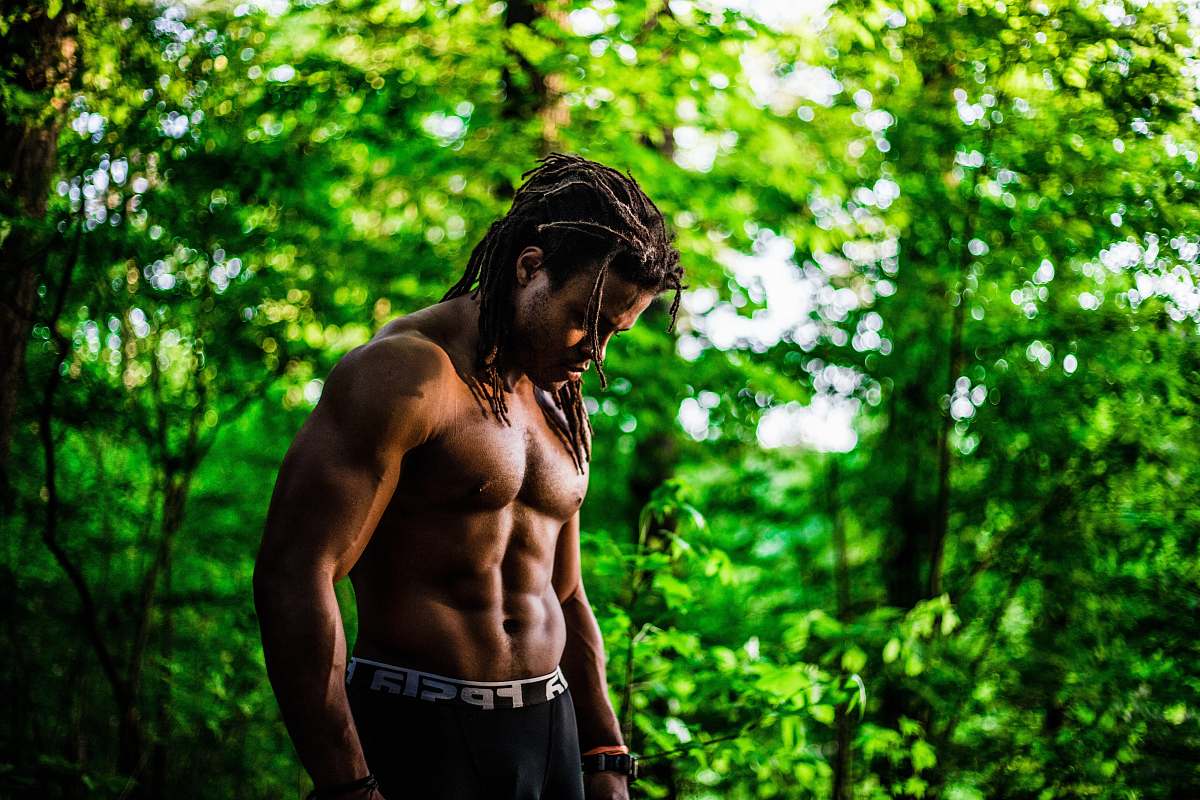 person topless man looking down near green trees during daytime man