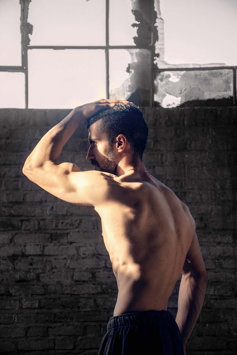person topless man placing his right hand on his head arm
