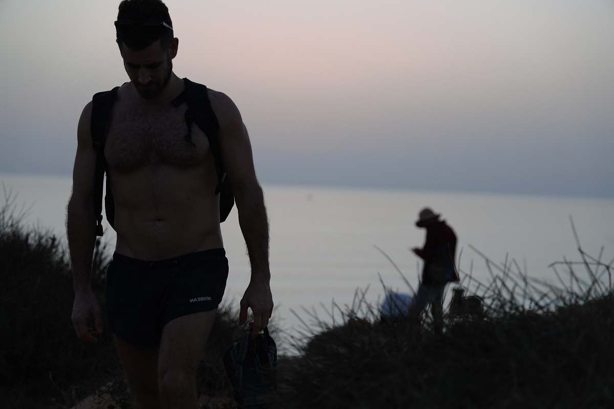 person topless man walking shorts