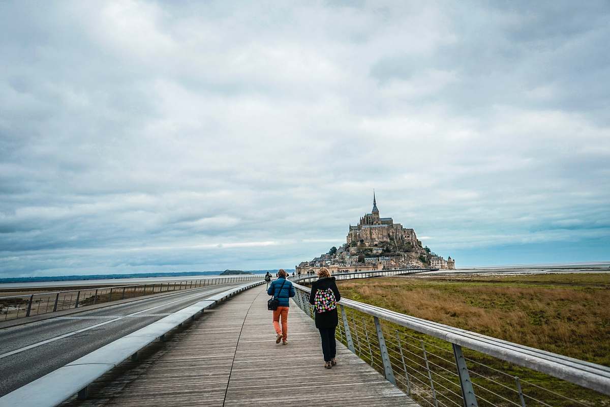 person two person walking on pathway near road boardwalk