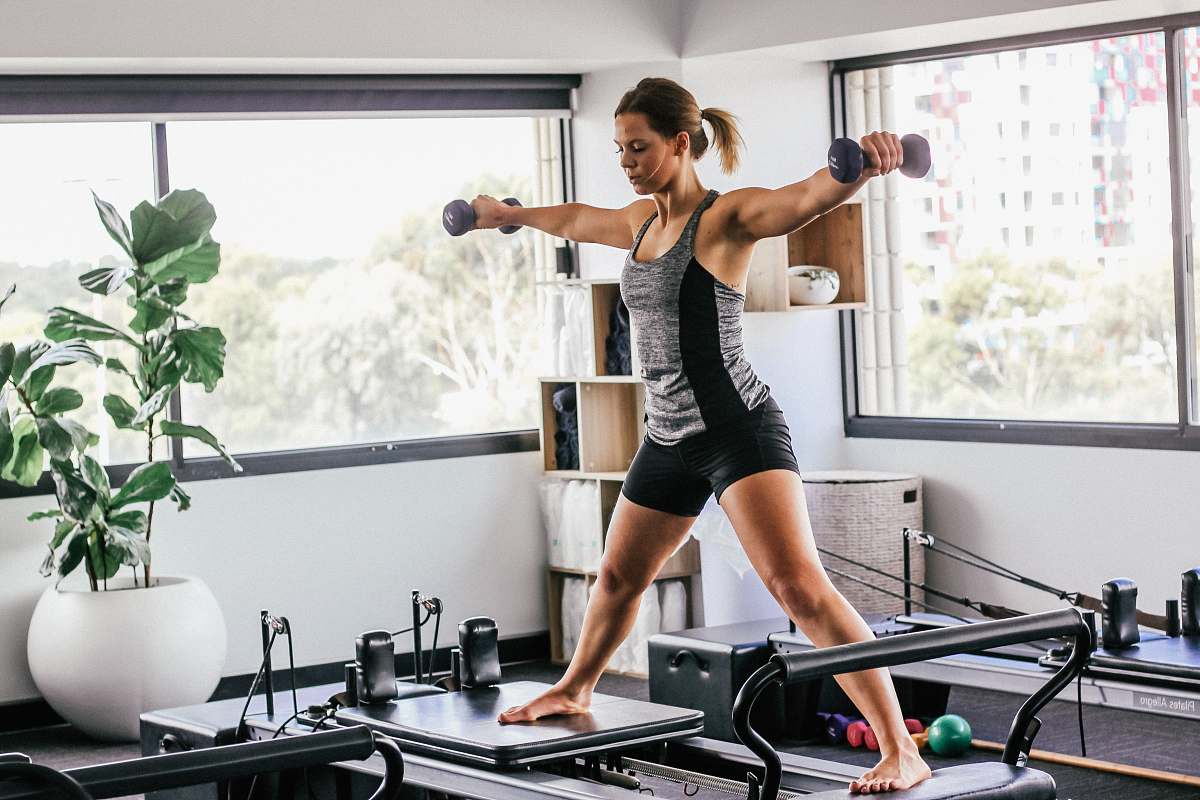 person woman doing exercise inside white room fitness