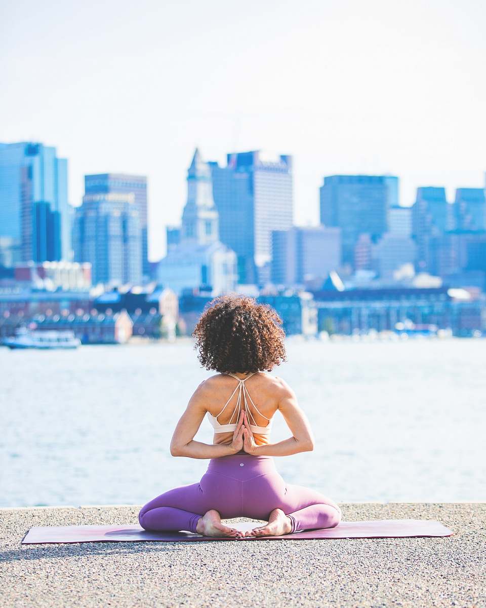 person woman doing yoga facing calm body of water fitness