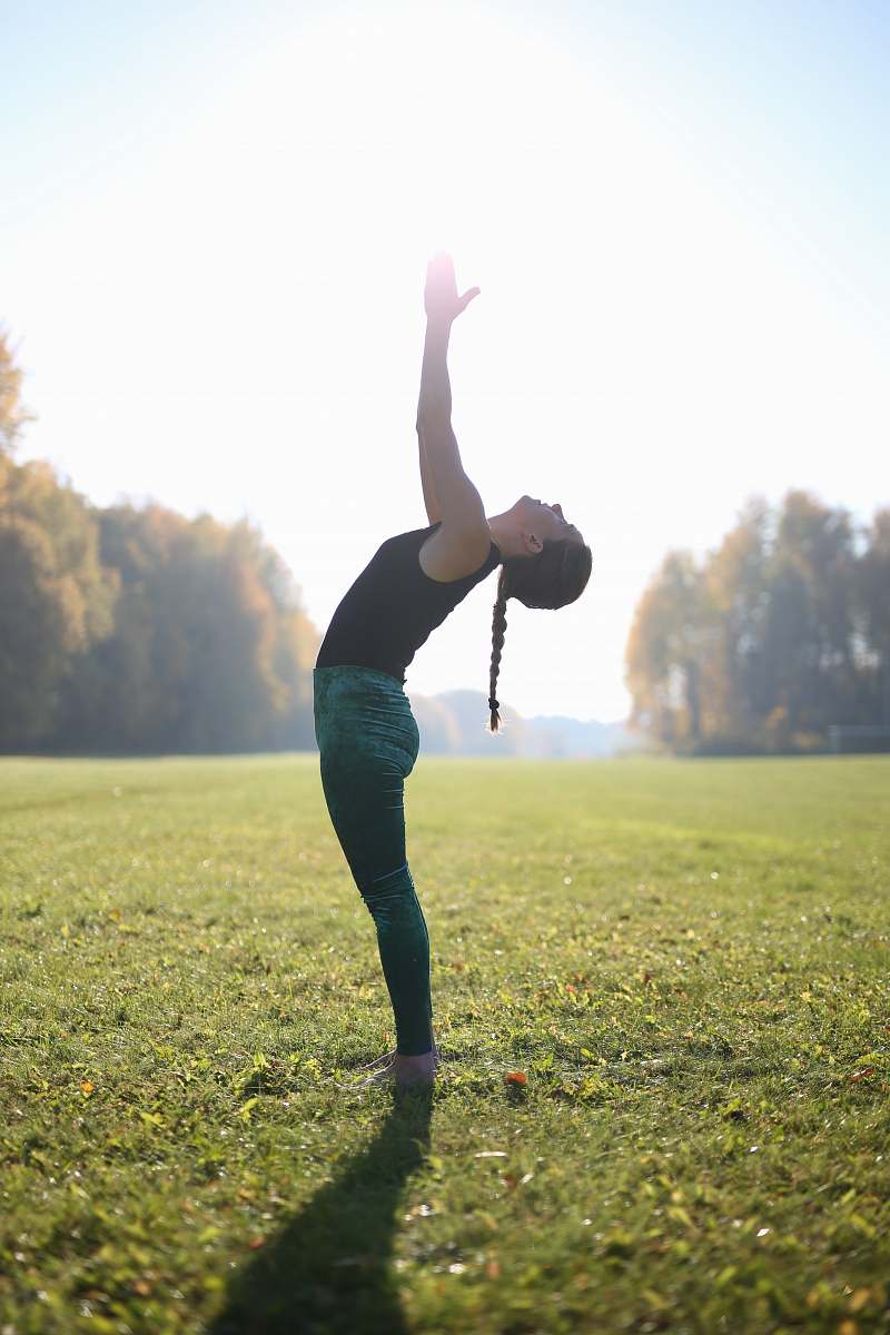 person woman doing yoga on grass field during daytime grass