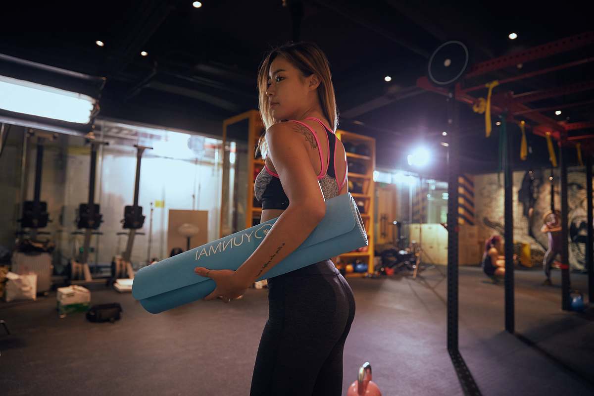 person woman holding blue exercise mat working out