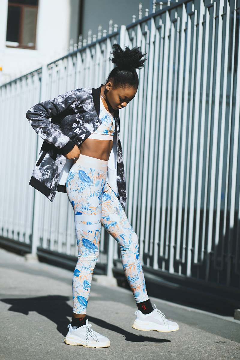 person woman in blue-and-white tracksuit near white metal gate during daytime people