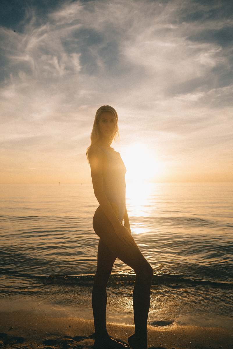 nature woman in swimsuit strike a pose at the beach during sunset outdoors