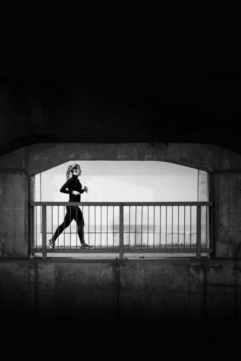 person woman jogging near grey metal hand rail black-and-white
