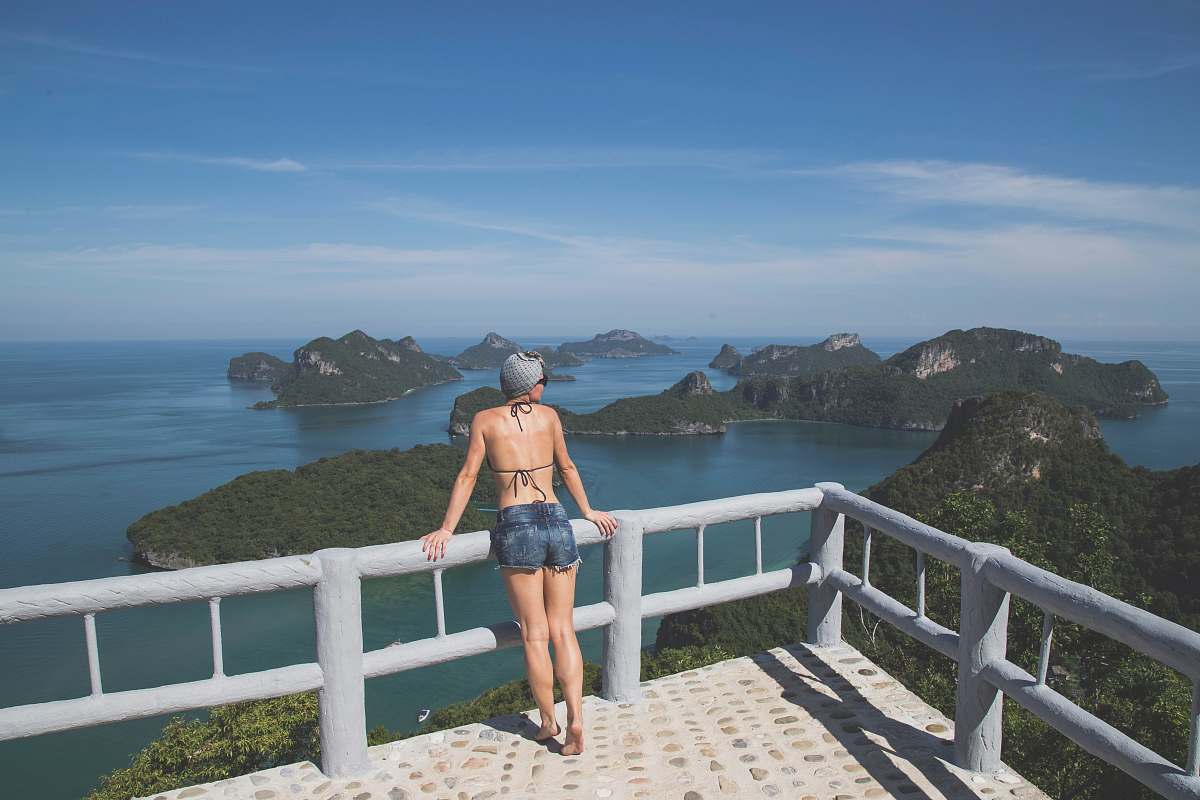 person woman leaning on railings facing islands ocean