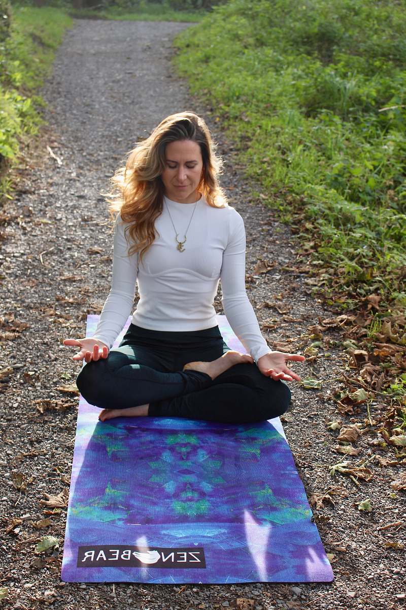 person woman meditating on dirt pathway with blue Yoga mat sleeve
