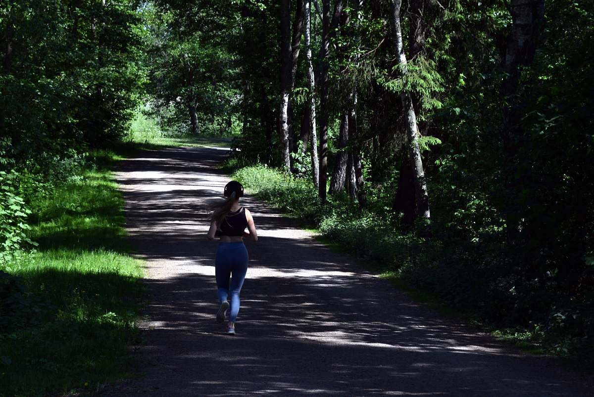 person woman running near green trees sport