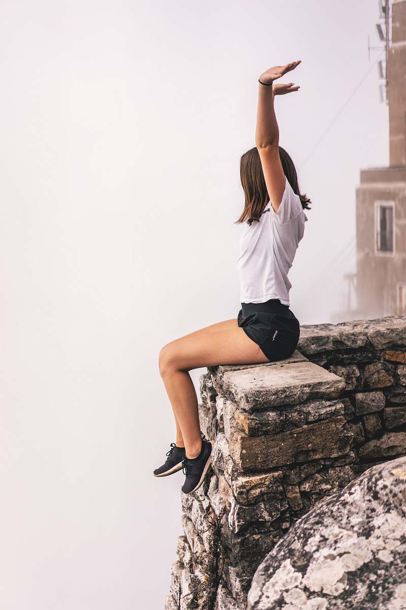 apparel woman sitting on edge while raising hand clothing