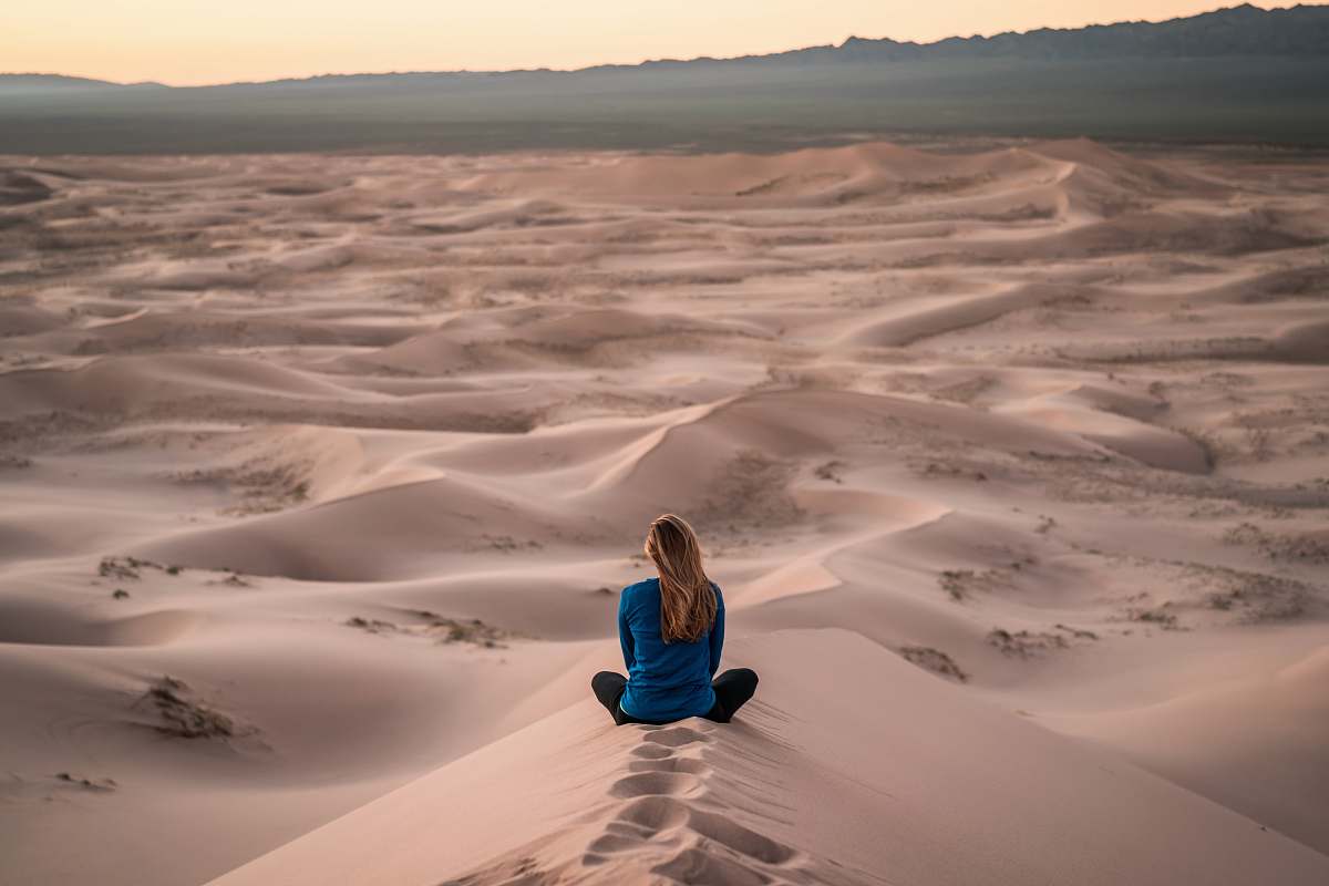 person woman sitting on sand field people