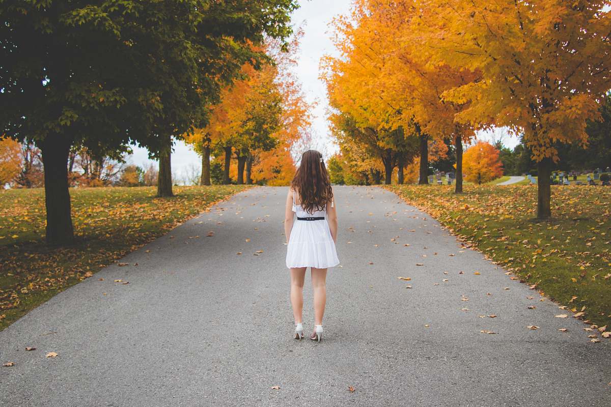 person woman standing on road near trees at daytime people