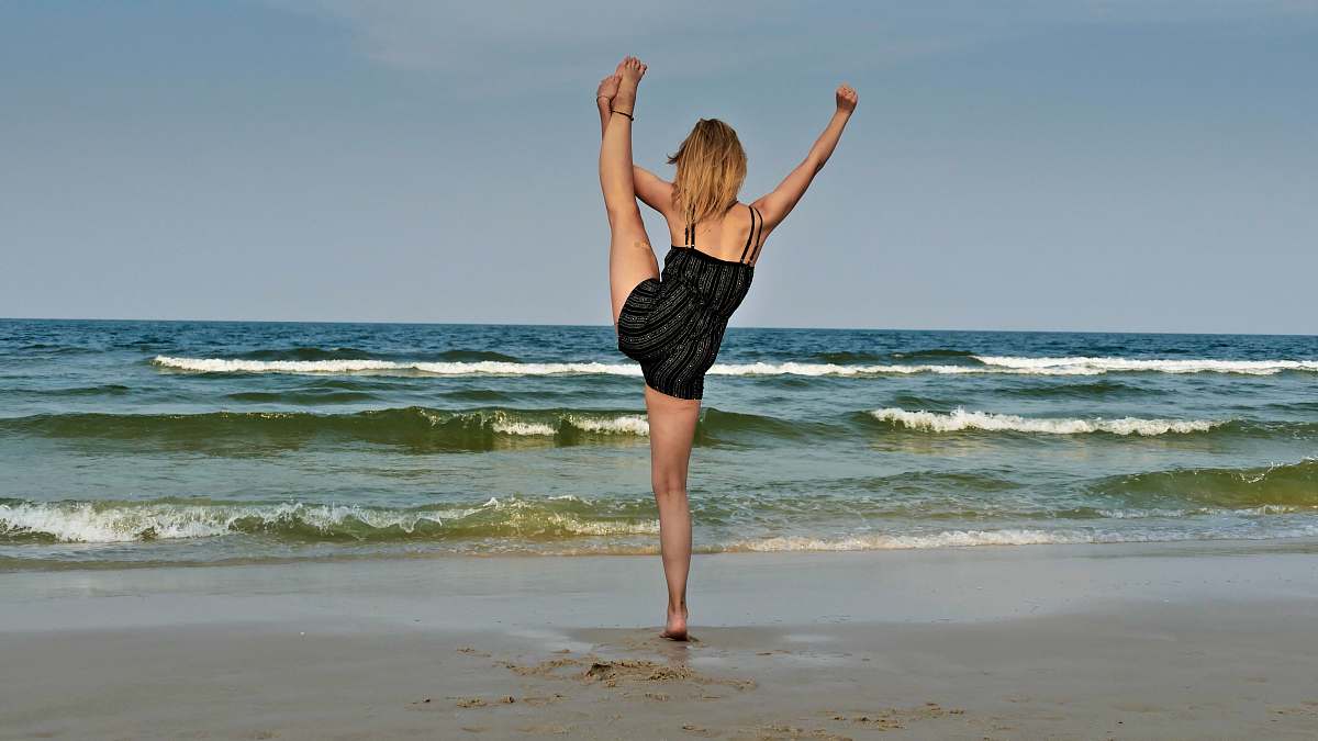 person woman standing on seashore dance pose