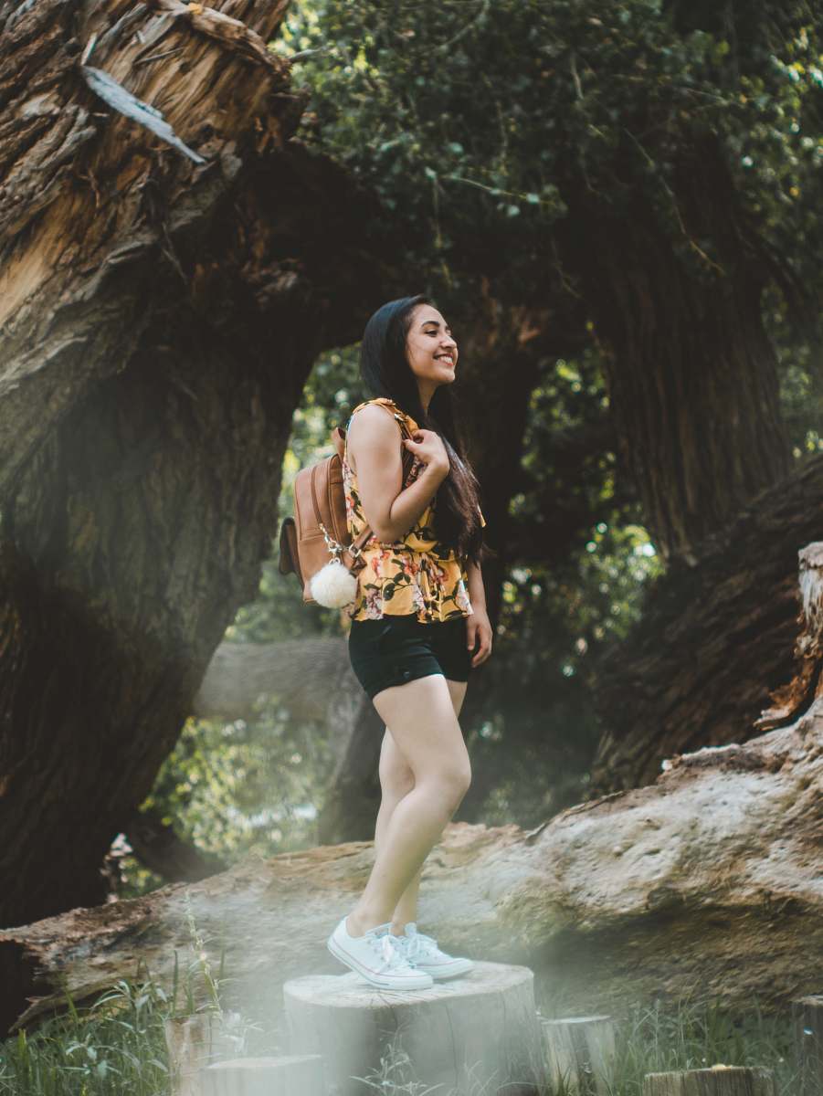 person woman standing on tree trunk beside tree people