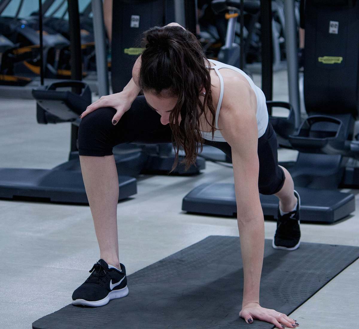 person woman stretching legs and arms on black yoga mat people