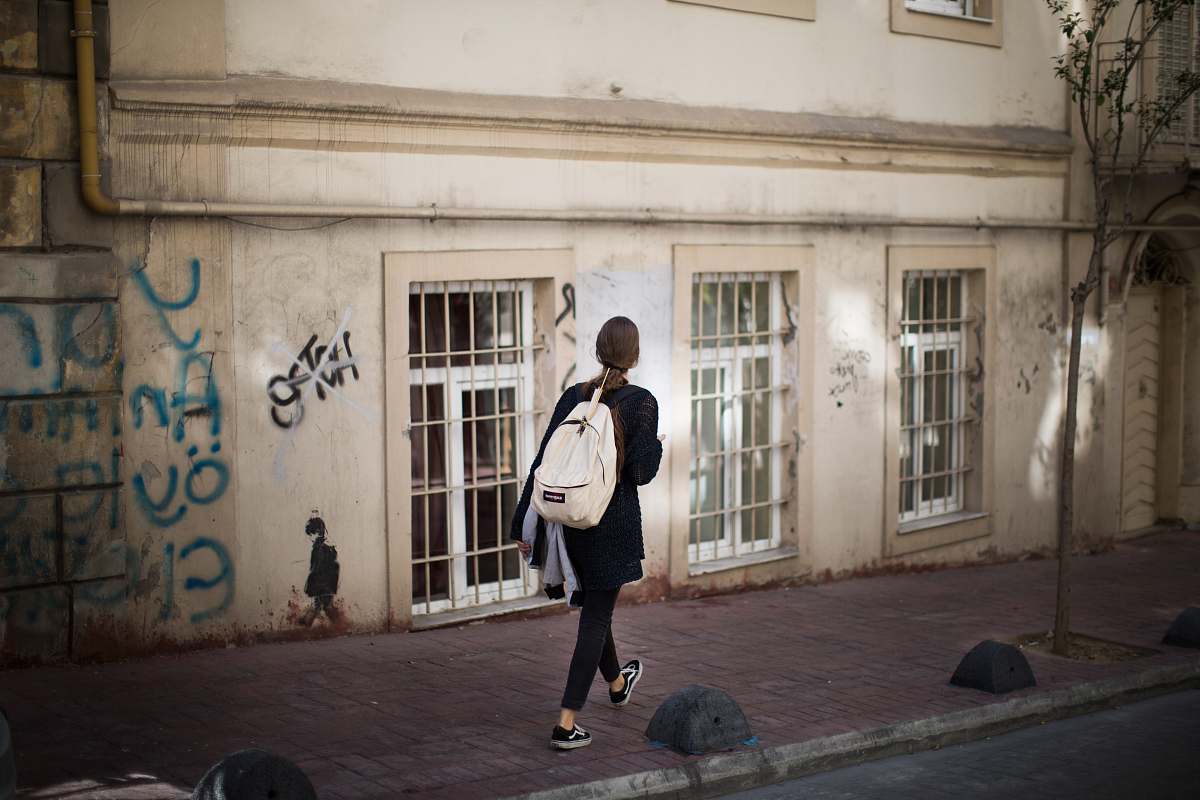 person woman walking on sidewalk nearby beige structure people