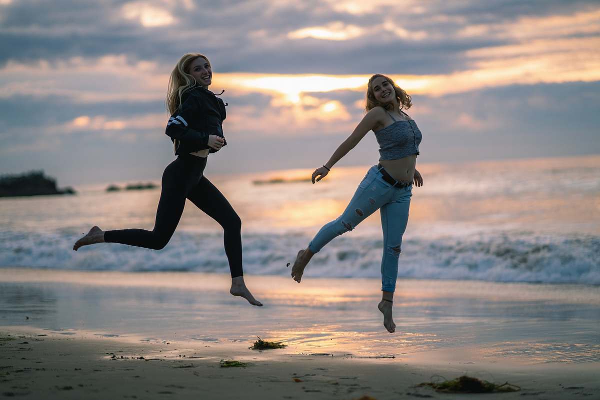 person woman wearing blackjacked and black leggings jumping on seashore sports