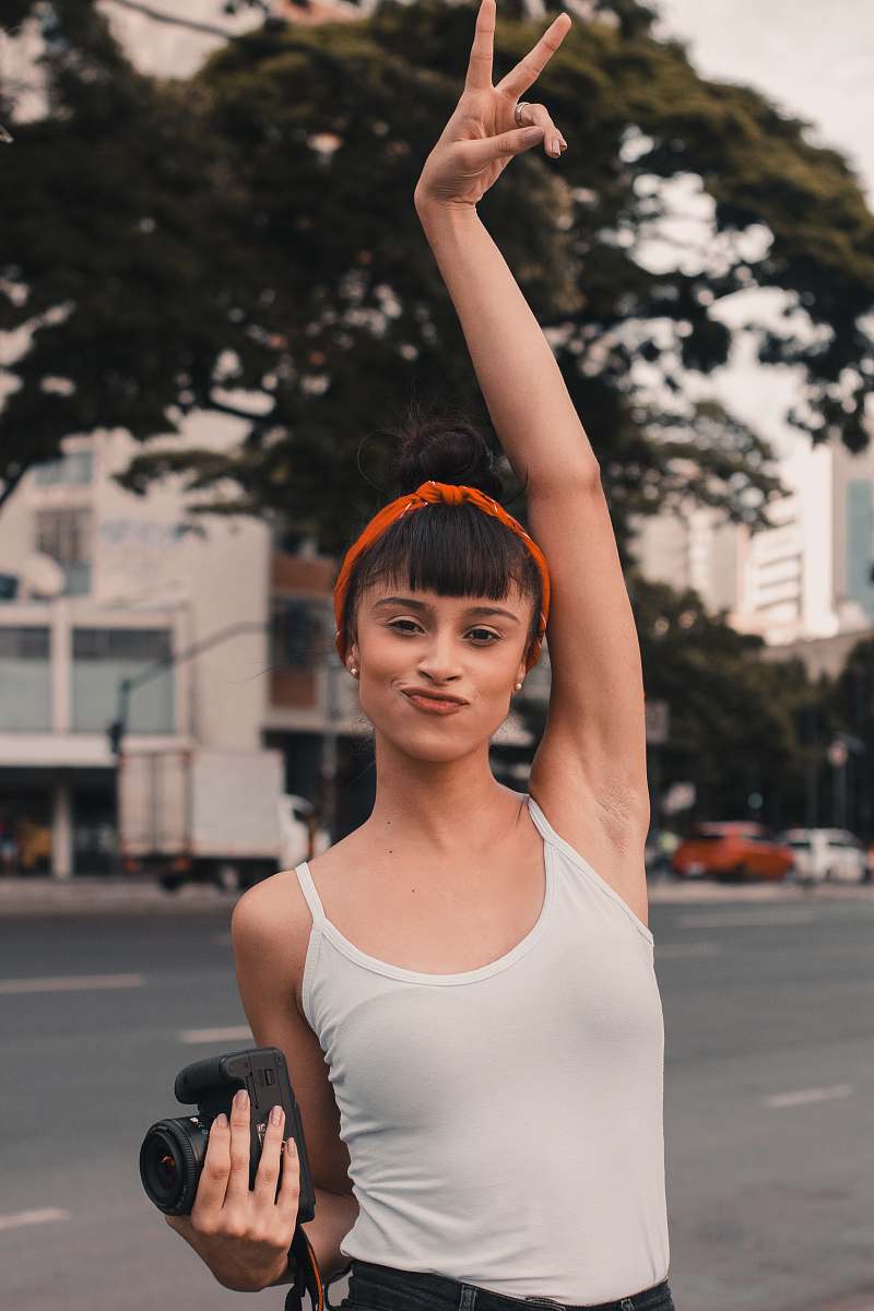 person woman wearing white tank top holding out peace sign during daytime clothing