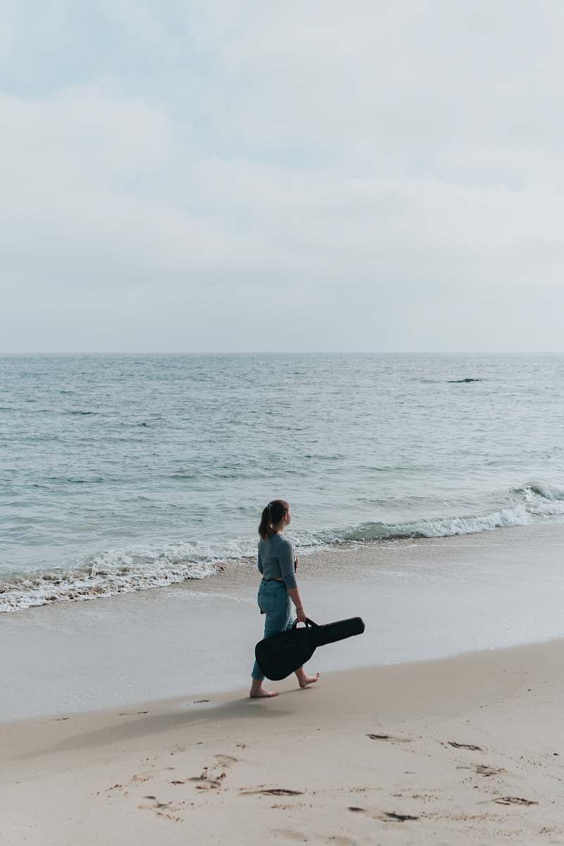 person woman with gig bag at beach outdoors