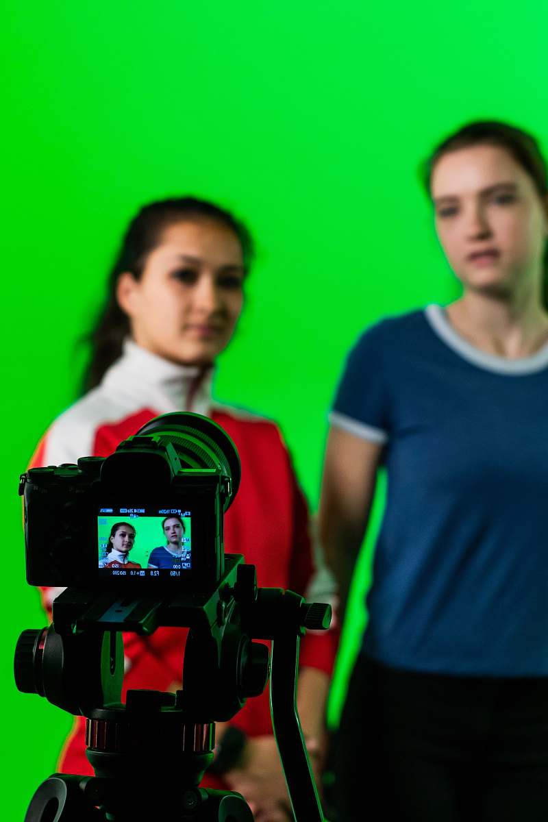 person women standing near green wall camera