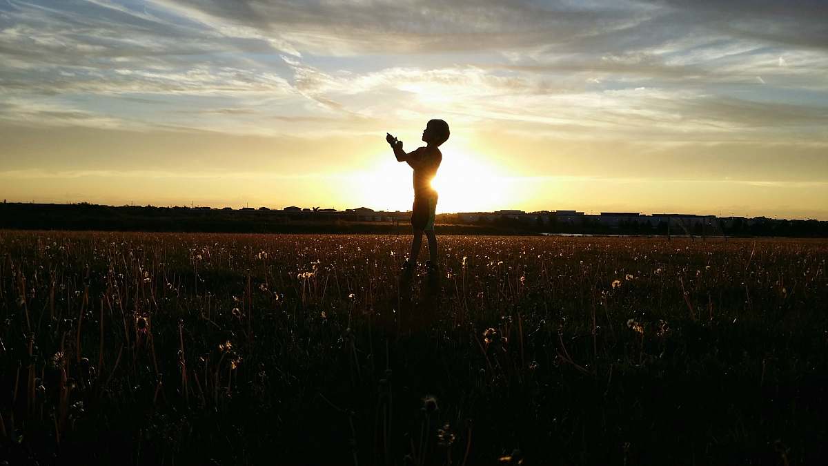sunset silhouette photo of a person lifting his hand sunrise
