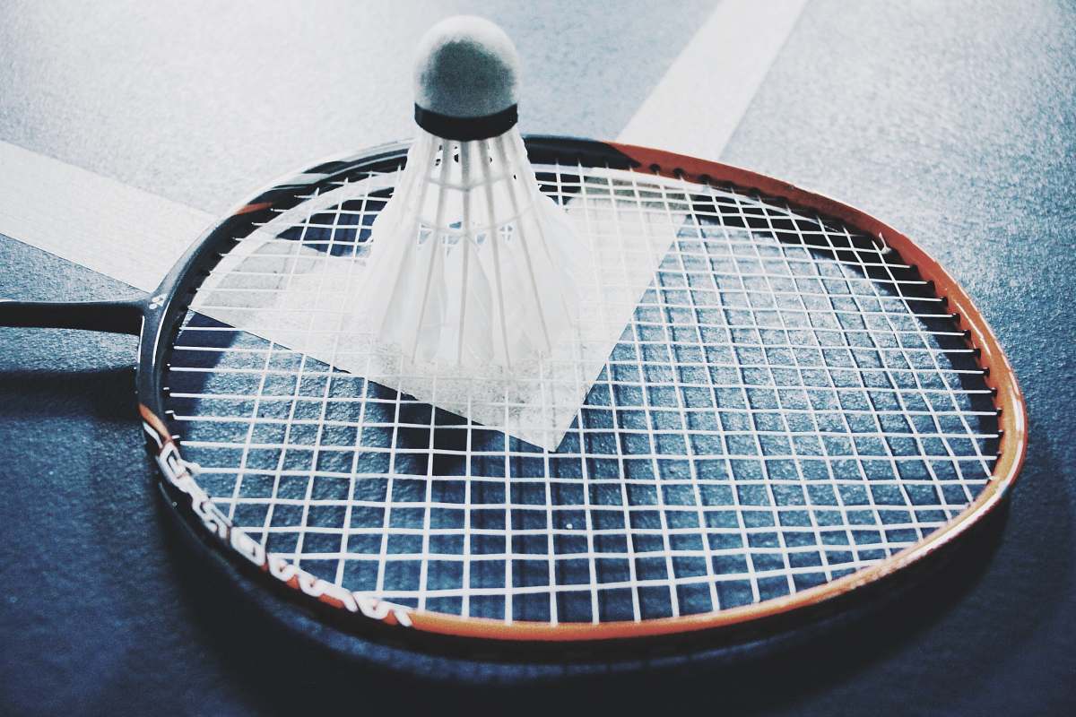 play white shuttlecock on brown and black badminton racket placed on floor game