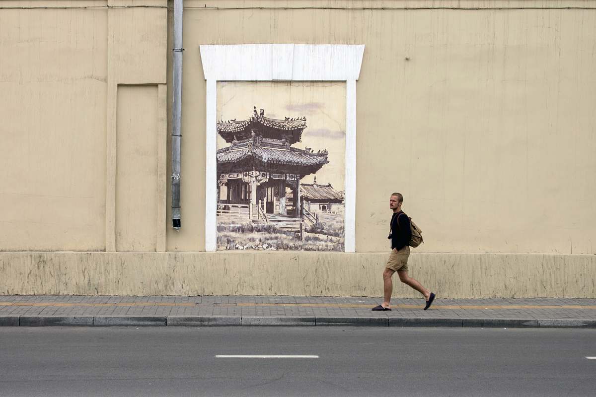architecture minimalist photography of man walking along pagoda wall artwork building