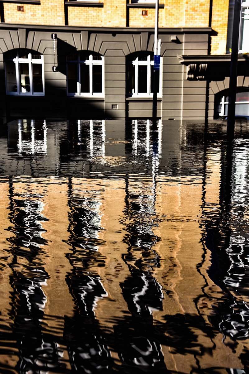 flood brown and yellow concrete building near body of water with self reflection water