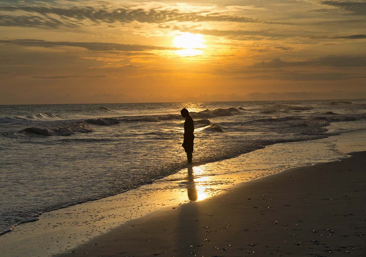 human person standing on body of water during golden hour ocean
