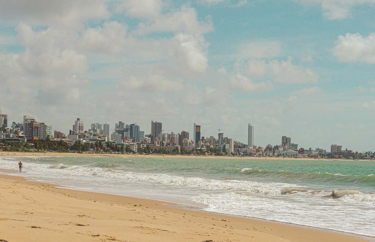 ocean person walking near seashore viewing calm sea and high-rise buildings outdoors