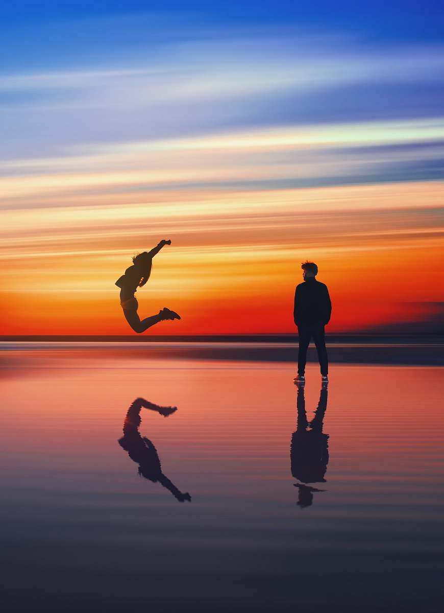 sea man near woman jumping near body of water beach
