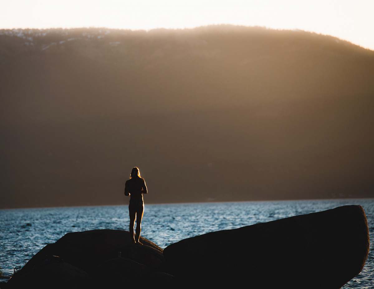 sea person standing on gray stone near body of water lake tahoe