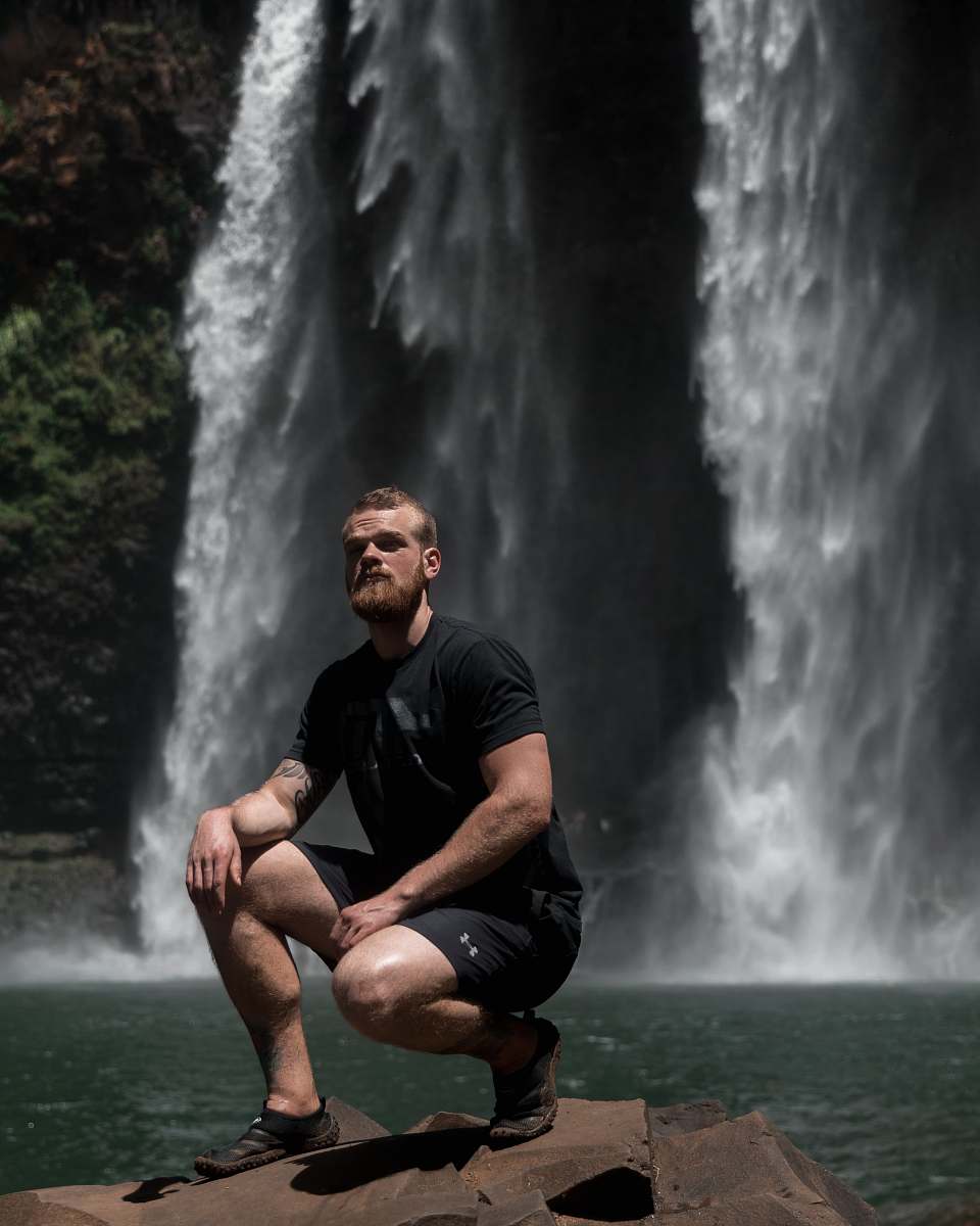 nature man sitting on rock near waterfalls river