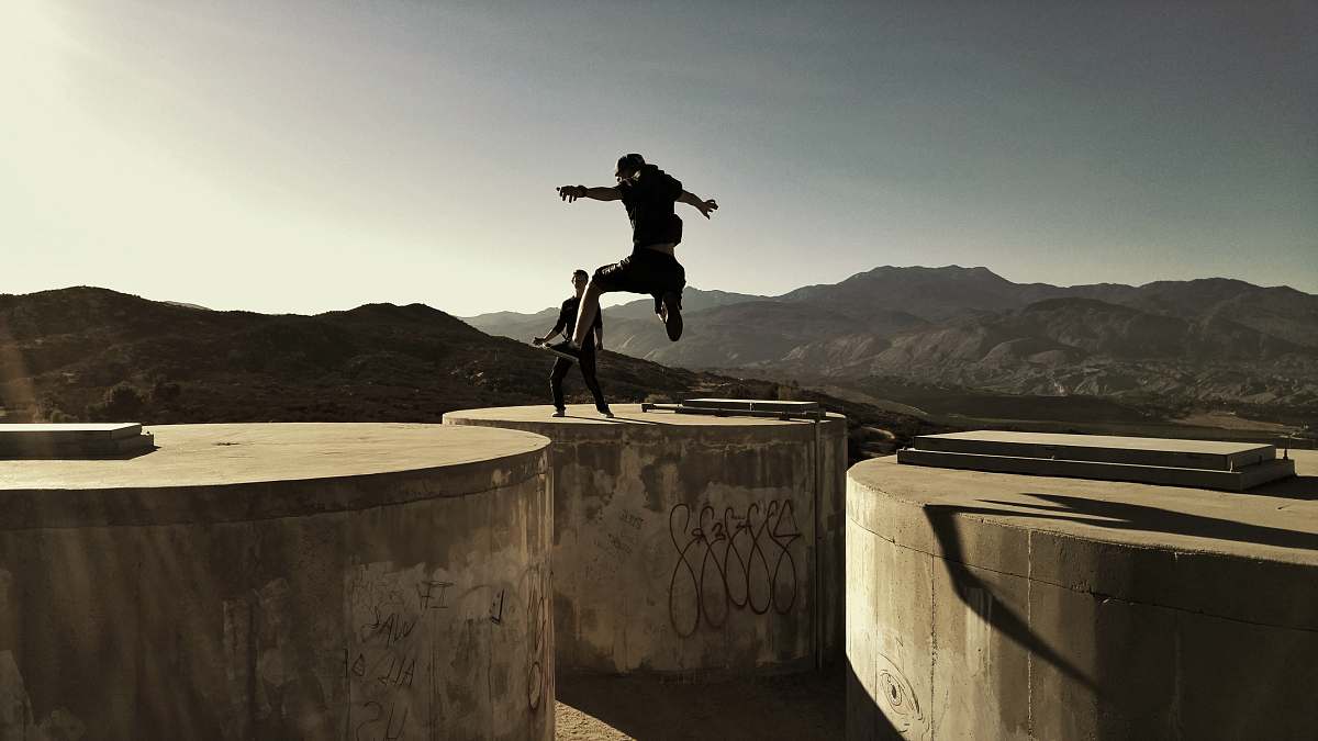 jump man jumping between two cylinder buldings outdoor