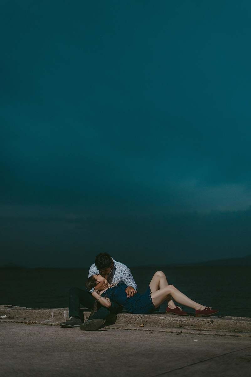 couple man kissing woman while sitting on railings during night love