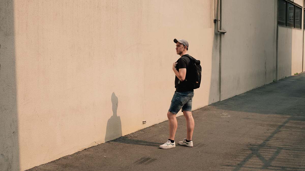 person man standing beside white concrete wall human