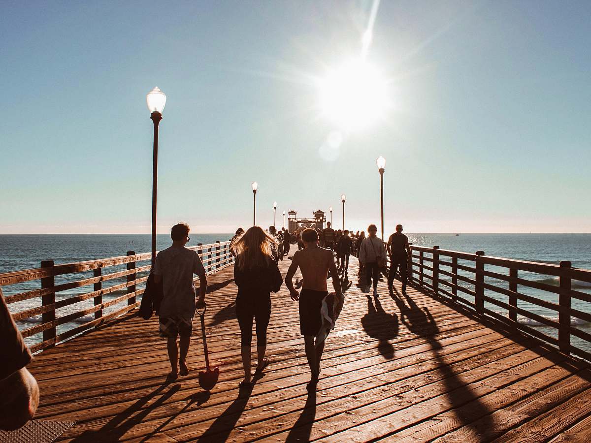 person people walking towards on brown wooden dock human