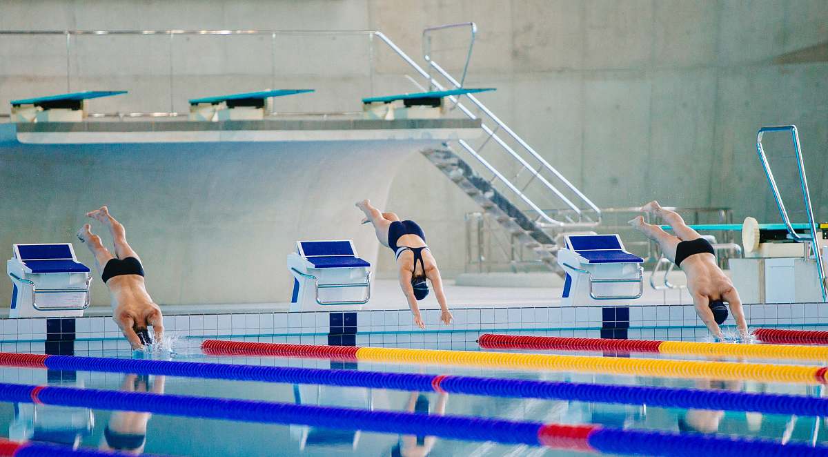 swimming three swimmers jumping on swimming pool water