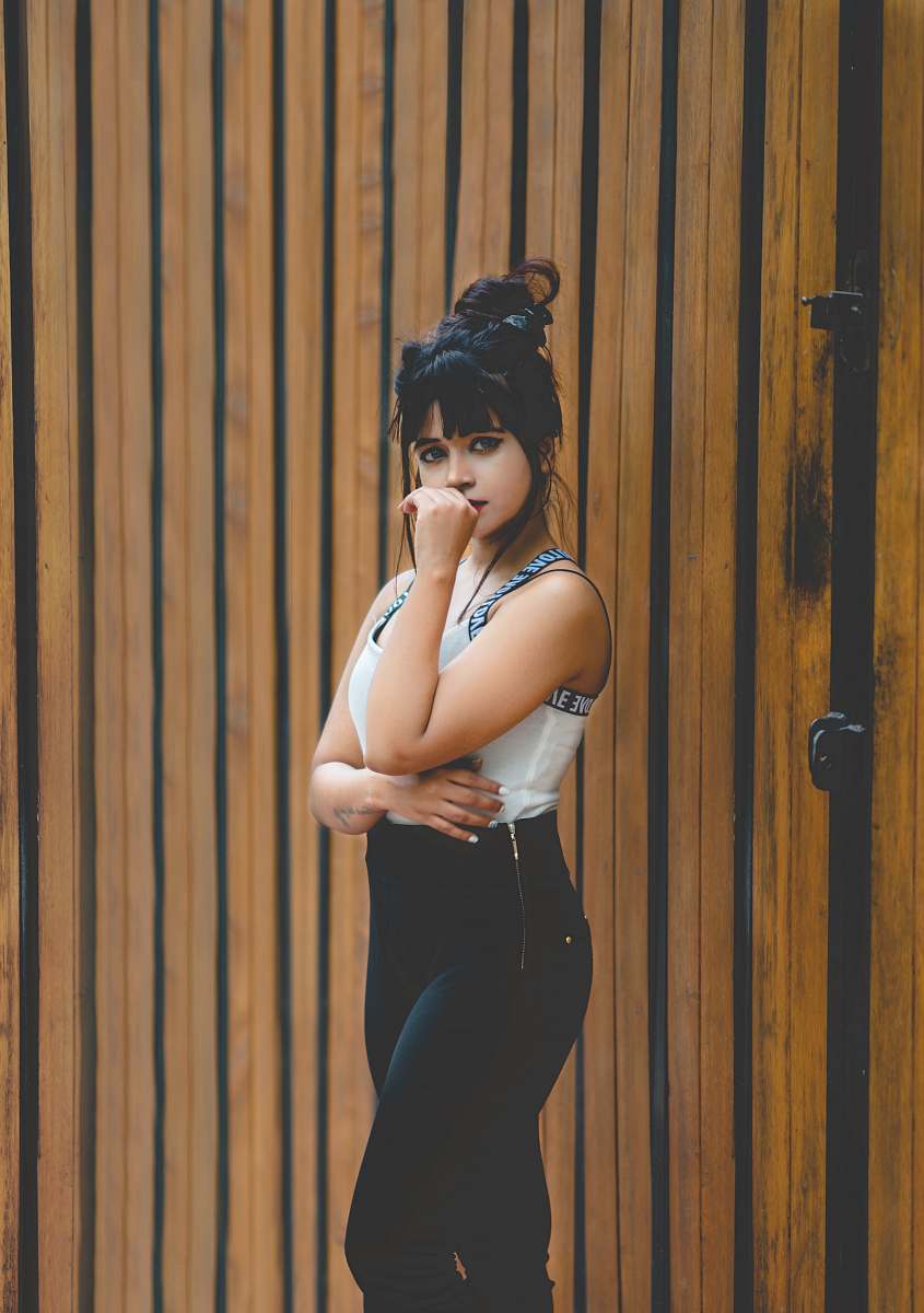 person woman standing near brown wooden wall at daytime human