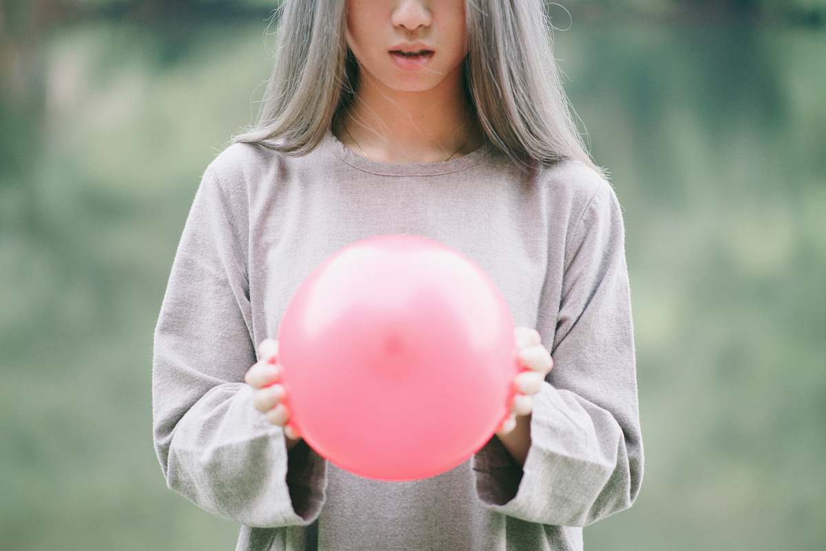 human girl in grey long-sleeved shirt holding pink balloon people