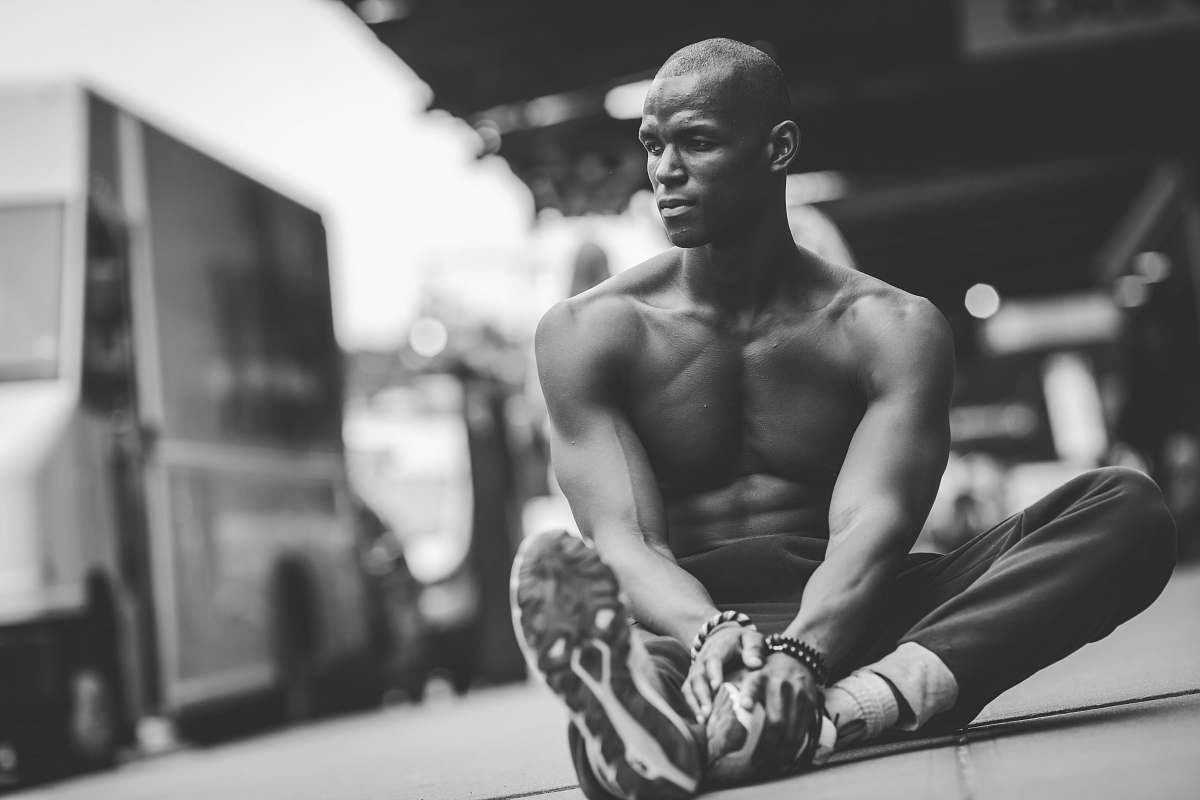 human grayscale of photo of topless man sitting on road black-and-white