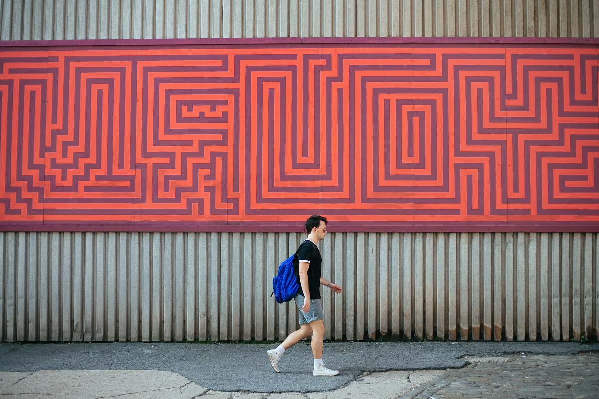 human man carrying blue backpack walking along pathway people