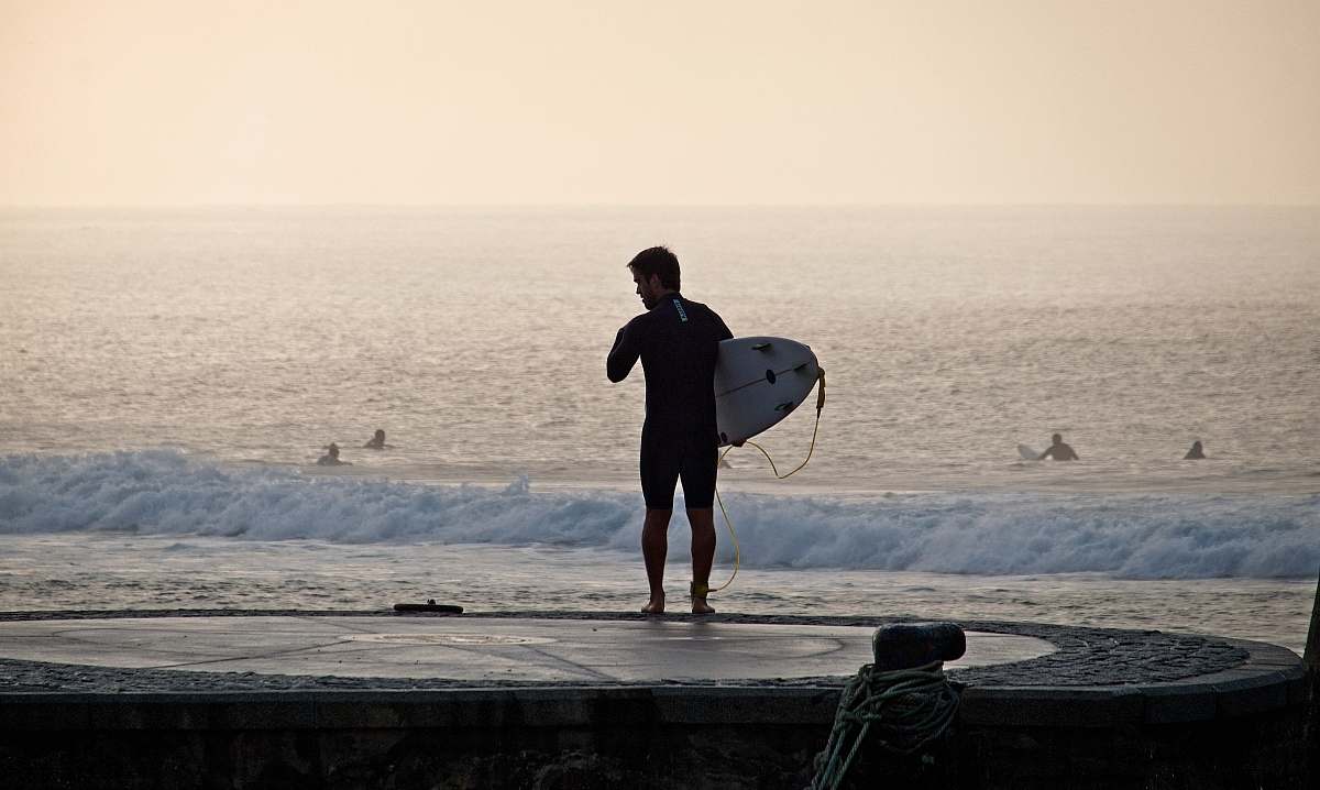 human man holding surfboard near seashore people