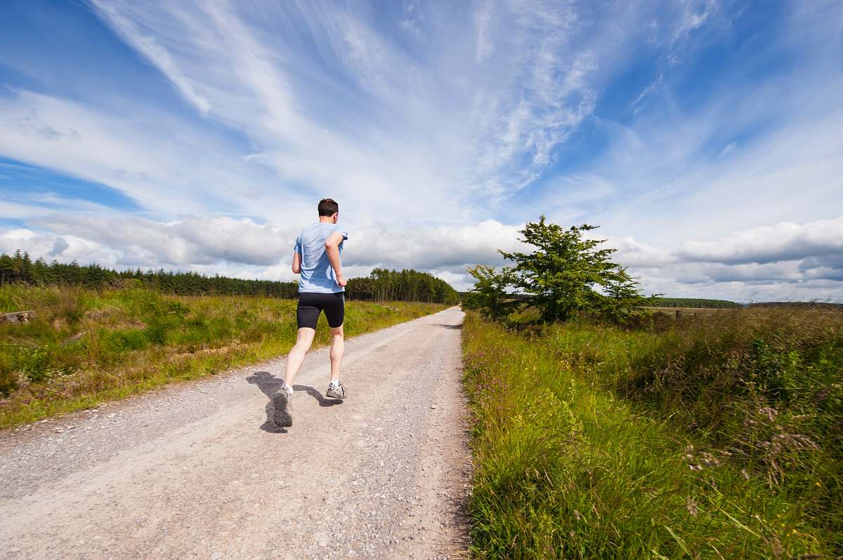fitness man running on road near grass field exercise