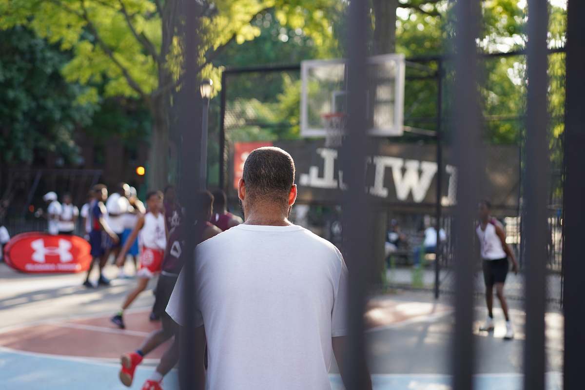 human man sitting on basketball court pedestrian