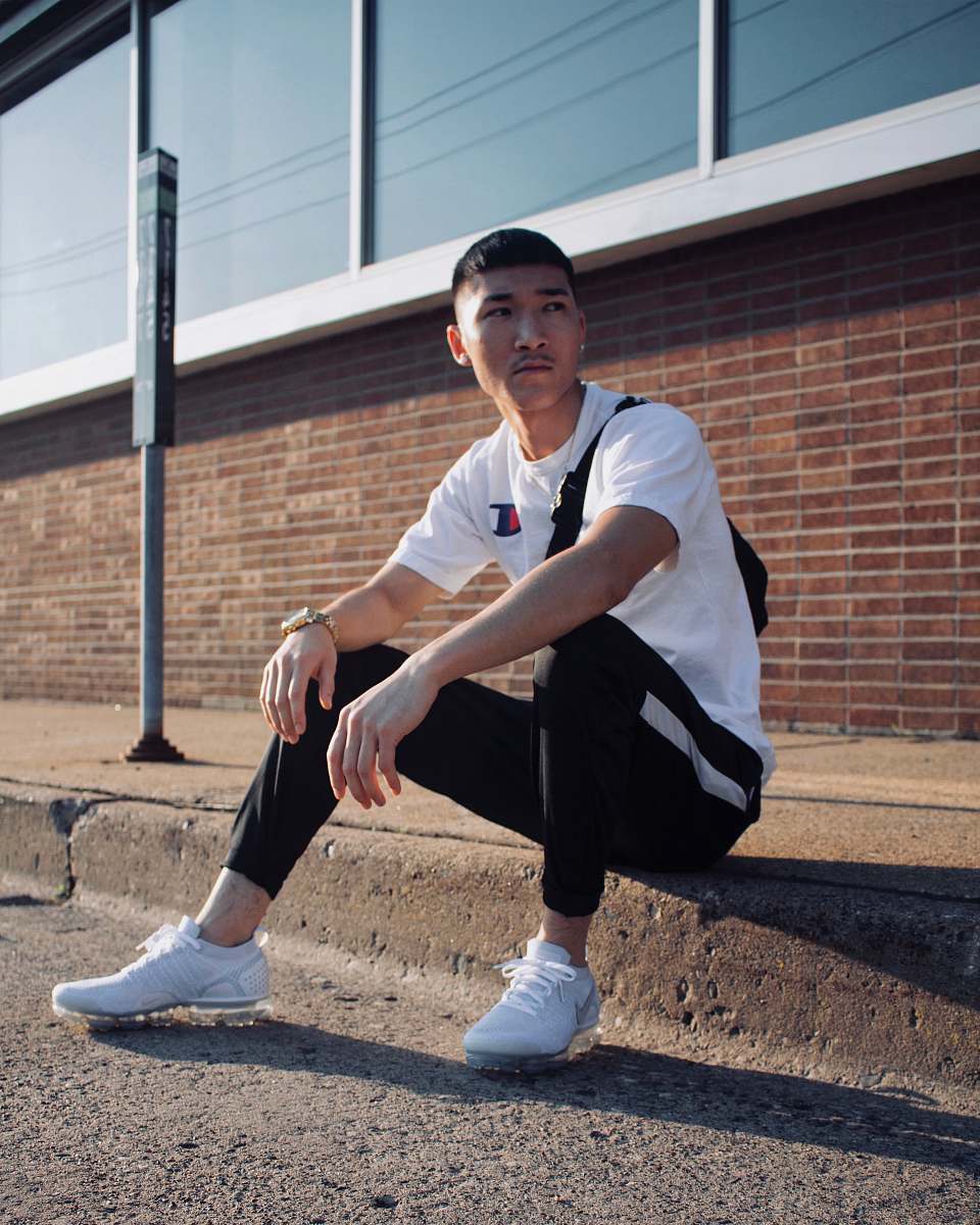 human man sitting on curb during day clothing