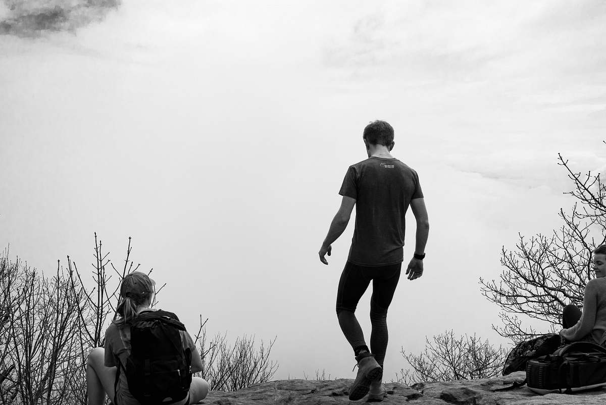 people man walking near bare trees black-and-white