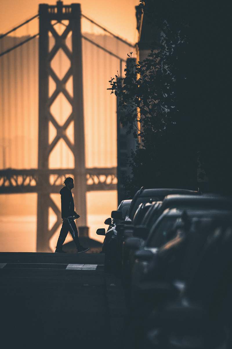 human man walking near parked cars during day indoors