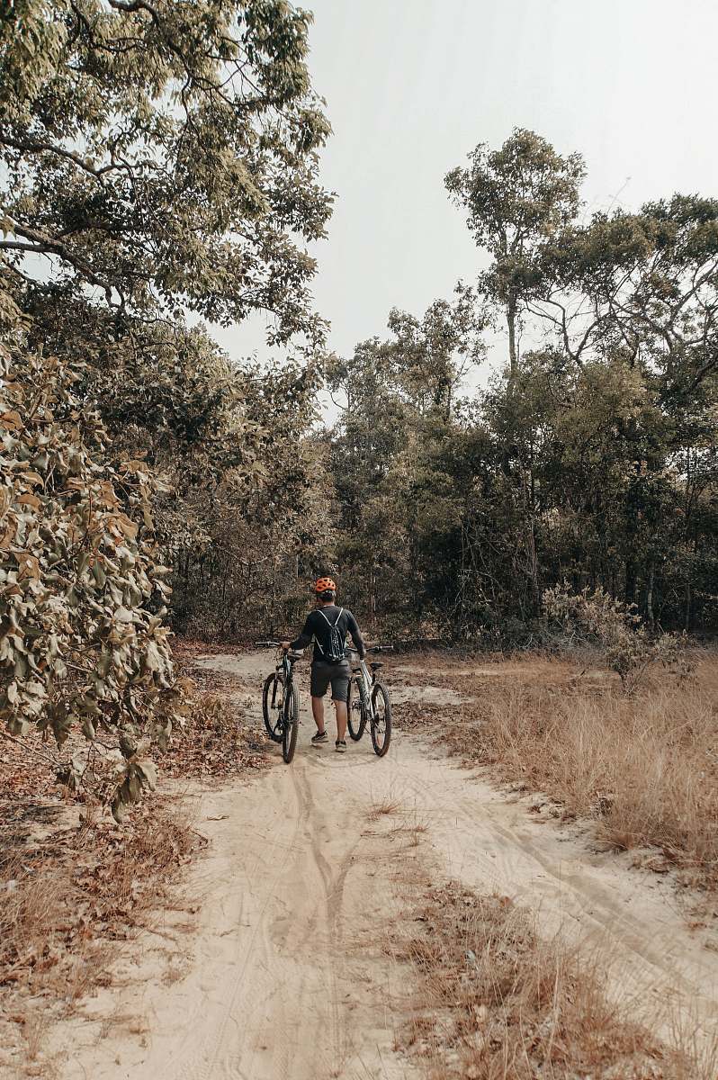 human man walking while holding on to two bicycles bicycle
